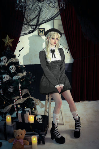 Gothic Lolita fashion model in grey dress with white lace collar, sitting by black Christmas tree with skull ornaments and candles