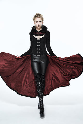 Woman in Gothic alternative fashion wearing a black coat with dramatic red lining, corset-style front, leather pants, and platform boots