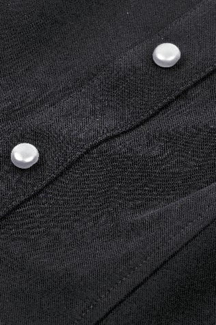 Close-up of pearl-style buttons and textured black fabric on Gothic blouse