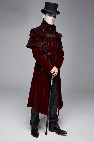Man in a long deep red velvet Victorian-style coat with black embroidered detailing and a matching capelet, wearing a tall black top hat and holding an ornate cane, standing on a light gray background."