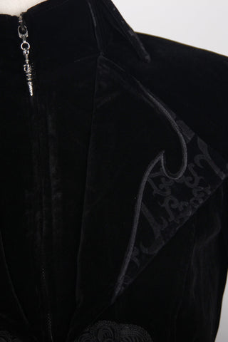 Close-up of a Gothic black velvet tailcoat showing high collar, zipper pull, and ornate brocade lapel detail.