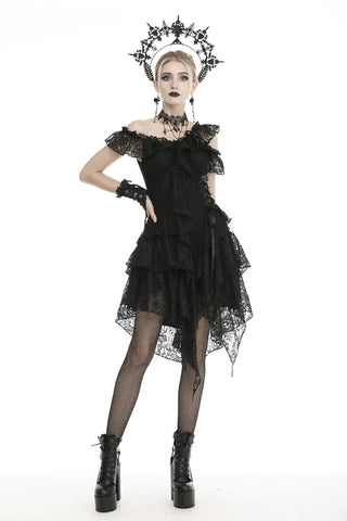 A model wearing a black off-shoulder mini dress with lace detailing and a flowing layered hanky hem. The outfit includes a frilly neckline, black gloves, and platform shoes, accessorized with a dark floral crown.