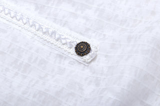 Close-up of decorative antique bronze button on white gothic dress trim