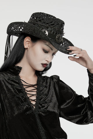 Model in black lace‑up Gothic blouse tipping a black western‑style hat with silver conchos and moon emblem.