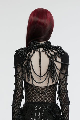 Back view of black Gothic beaded shoulder and neck cape with cascading strands and skull accents on a model with long red hair.
