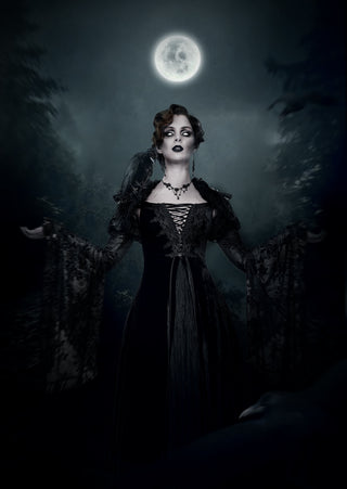 Gothic woman in a black lace dress under a full moon, dramatic Halloween vampire-inspired look in a dark forest.