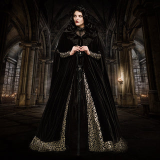 Woman in a black velvet cloak with gold trim standing in a Gothic cathedral, styled for a masquerade ball or vampire-inspired formal event.