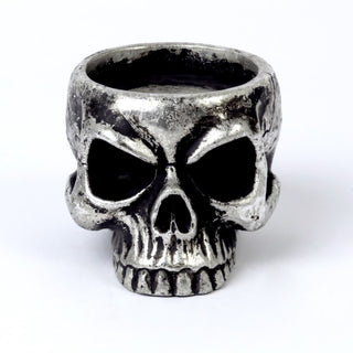 Front view of an antique silver skull tea light holder on a white background