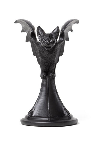 Front view of a black bat taper candle holder with sculpted wings on a white background
