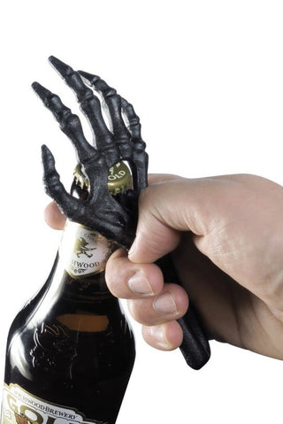Cast iron skeleton hand bottle opener being used to remove a bottle cap