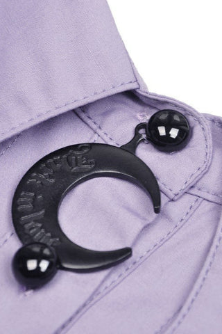 Close-up of black crescent moon pendant on bat collar of violet shirt