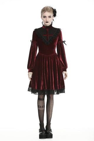 Woman wearing a deep red velvet Gothic dress with black lace trim and cross neckline detail.
