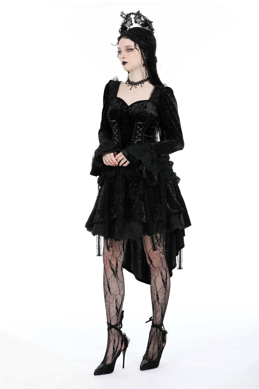 Model in a black Gothic high-low dress with lace sleeves, corset bodice, and crown, posing with arms crossed on a white background.