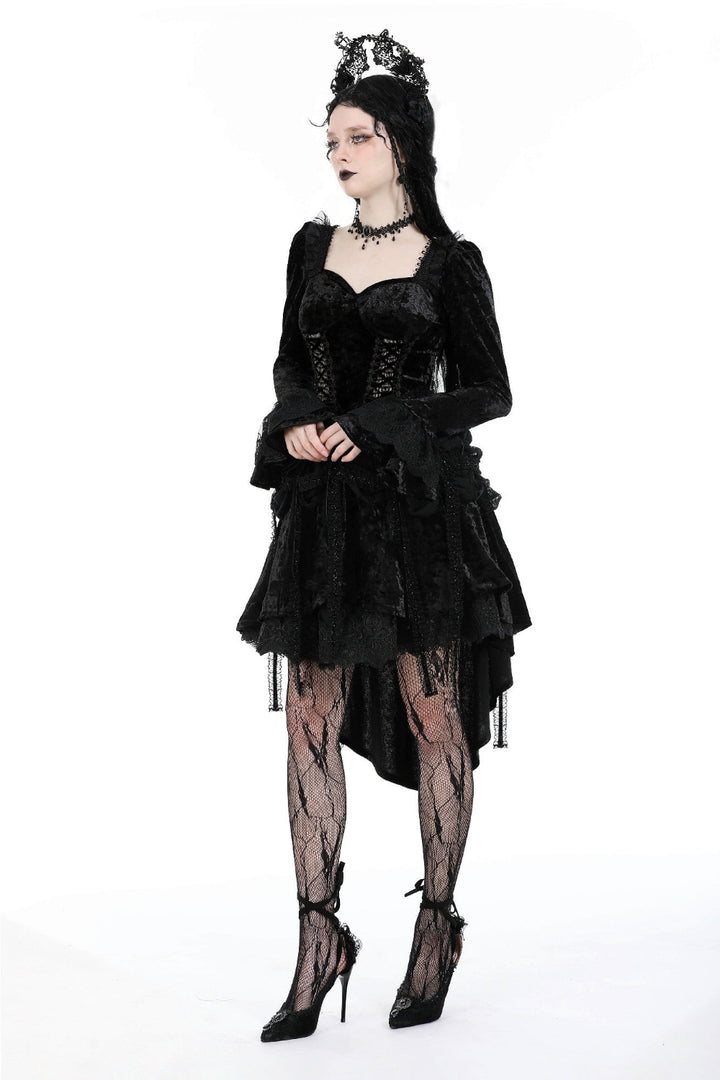 Model in a black Gothic high-low dress with lace sleeves, corset bodice, and crown, posing with arms crossed on a white background.