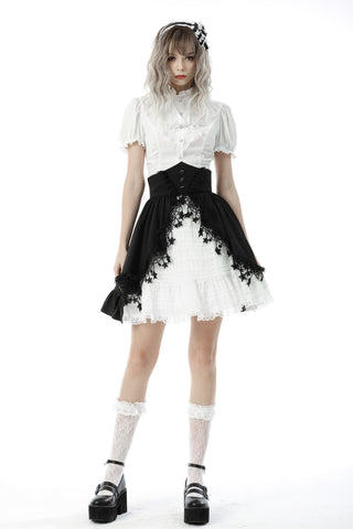 Model wearing a white Victorian-style puff-sleeve blouse with high collar, black corset belt, and layered white lace skirt with black lace overlay – standing against a white background.