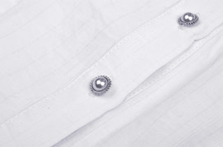 Close-up of white blouse fabric with decorative silver pearl-style buttons and fine stitched detailing.