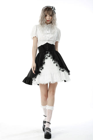 Model walking in a white Victorian-style blouse with puff sleeves and high collar, paired with a black corset belt and layered lace skirt – white background.