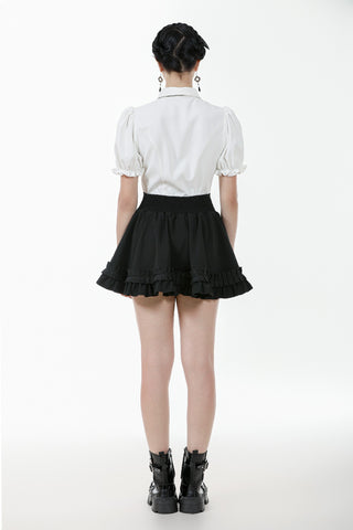 Back view of model in white puff-sleeve blouse and black mini skirt with lace trim, standing on white background