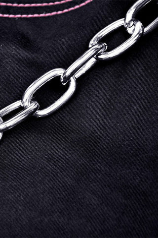 Close-up of silver chain detail on black fabric with pink contrast stitching