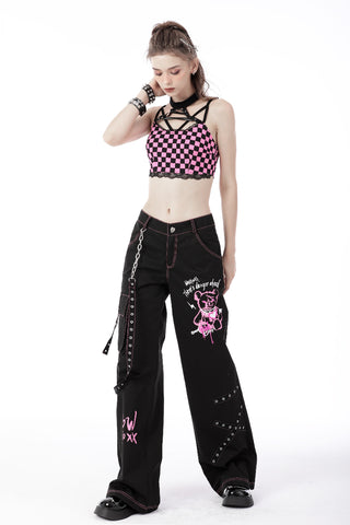 Model wearing black punk pants with pink teddy bear print, grommet details, and chain strap, paired with a pink checkered crop top on white background