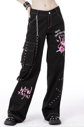 Model wearing black Y2K punk cargo pants with pink graffiti bear print, metal chain, heart button, and side pocket straps.