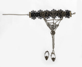 Flat lay of Devil Fashion AS057 Steampunk hand harness showing black lace cuff, antique brass gears, filigree centerpiece, and two connected finger rings on white background.