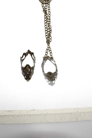Close-up of Devil Fashion AS057 hand harness showing two antique brass filigree finger rings connected by dual chain links.
