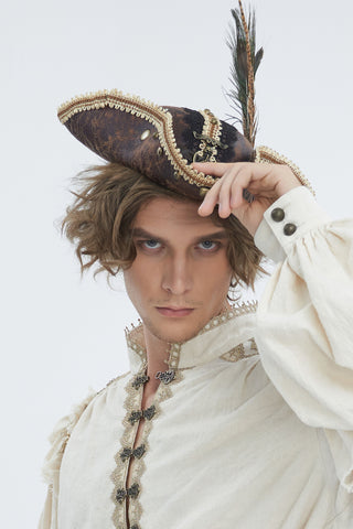 Model wearing a brown cracked-finish tricorn hat with gold trim, a tall feather plume and a skull-and-crossed-swords emblem.