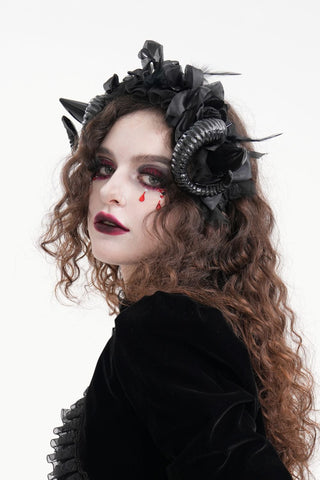 Model wearing a black devil horn headpiece decorated with feather roses and curled horns.