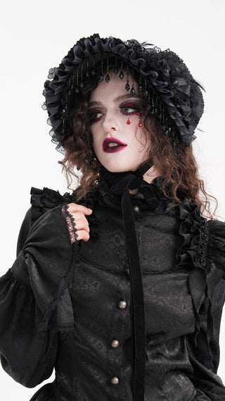 Model wearing Devil Fashion AS195 black Victorian-style dress with matching bonnet, featuring lace ruffles, bead fringe, and red tear-shaped face gems, posed against a white background.