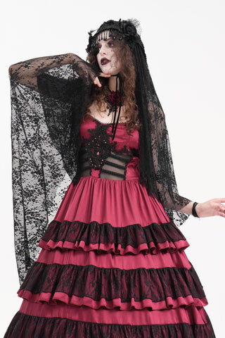 Model wearing a layered red and black Gothic dress with lace veil and bead-trimmed headdress, styled in a dark romantic bridal look.