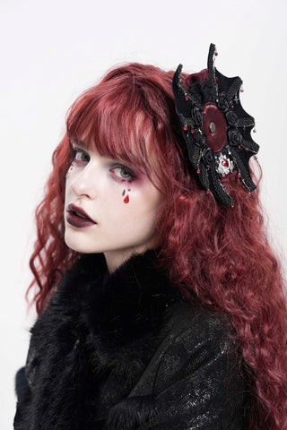 Model with long red hair wearing the Devil Fashion AS212 Batlace Rosette hair clip, a Gothic black and red bat-and-rose accessory styled against a white background.