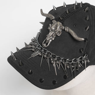 Close-up of black cap with horned skull emblem, spike studs, and chain trim on the brim.