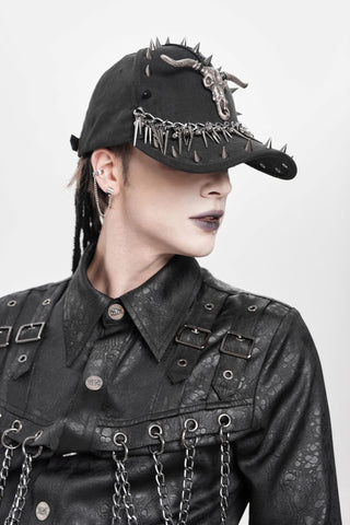 Side view of a black spiked cap with a horned skull emblem and chain trim, worn with a black textured jacket with metal hardware.