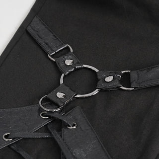 Close-up of a black leather harness with metal rings on a black background