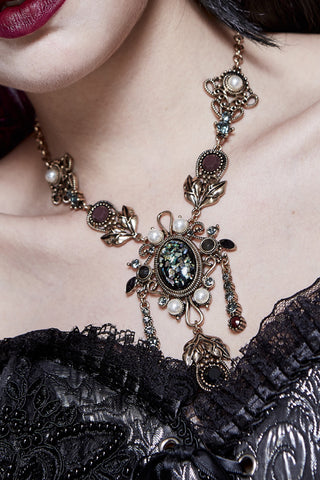 Close-up of eva lady eas006 Victorian Gothic necklace with iridescent cabochon, pearls, and antique gold filigree worn over black lace corset.