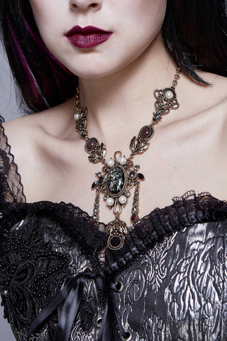 Model wearing Eva Lady EAS006 ornate Victorian Gothic necklace with iridescent cabochon, pearls, and antique gold filigree on a black corset.