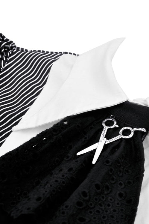 Close-up of white collar with black jabot and scissor charm