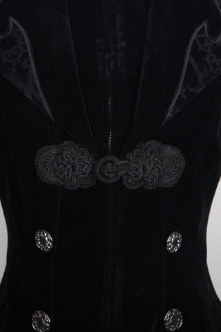 Close-up of a Gothic black velvet tailcoat showing ornate silver buttons, brocade lapels, and decorative frog closure at the chest.