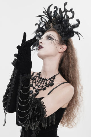 Black velvet opera gloves with lace trim and draped chain detailing worn above the elbow