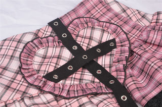 Close-up of black faux leather cross strap over heart patch on pink plaid skirt