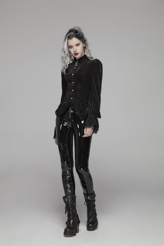 Model in a black striped button-front blouse with puff shoulders, fluted lace cuffs, and a pointed hem, turning to show the corset-laced back on a gray background.