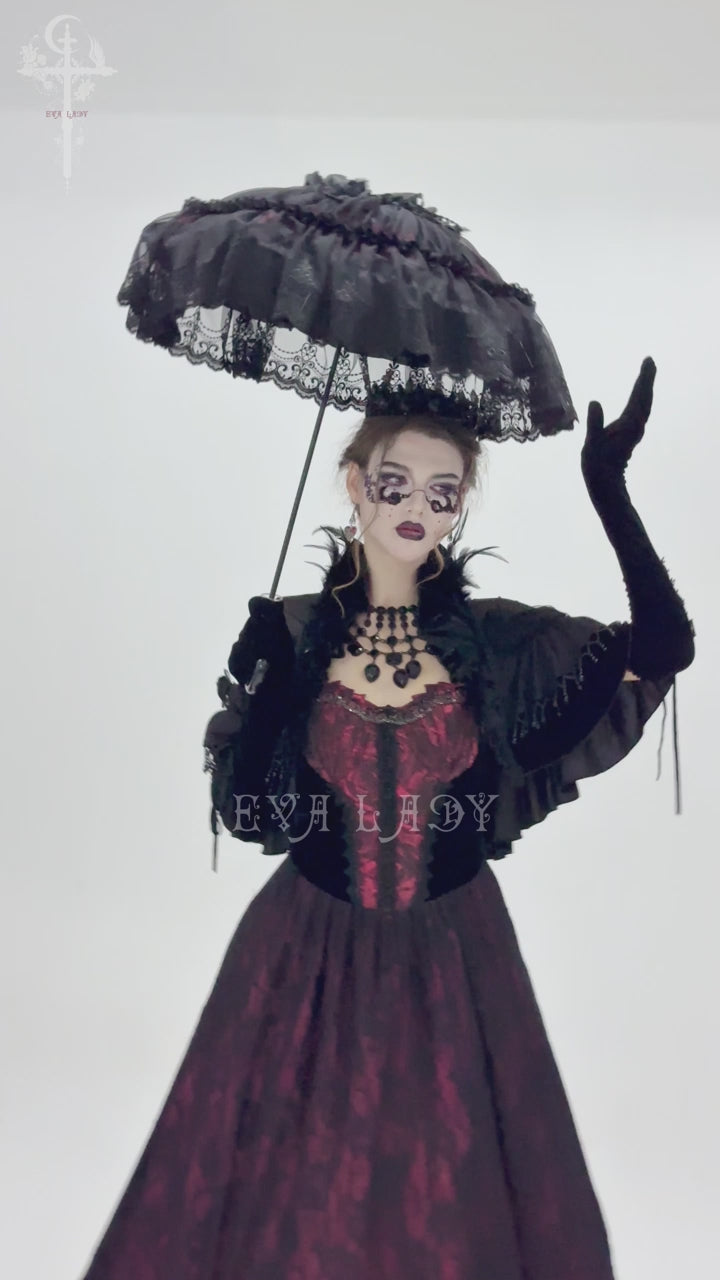 Close-up of a black lace Victorian-style parasol being held and tilted, showcasing ornate ruffles and embroidery against a white background.