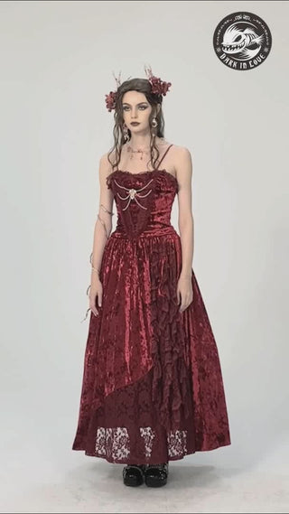 Model wears the Dark in Love DW757 red velvet ballgown, gently moving to show the layered asymmetric hem, corset-style bodice, and soft drape of the crushed velvet fabric.