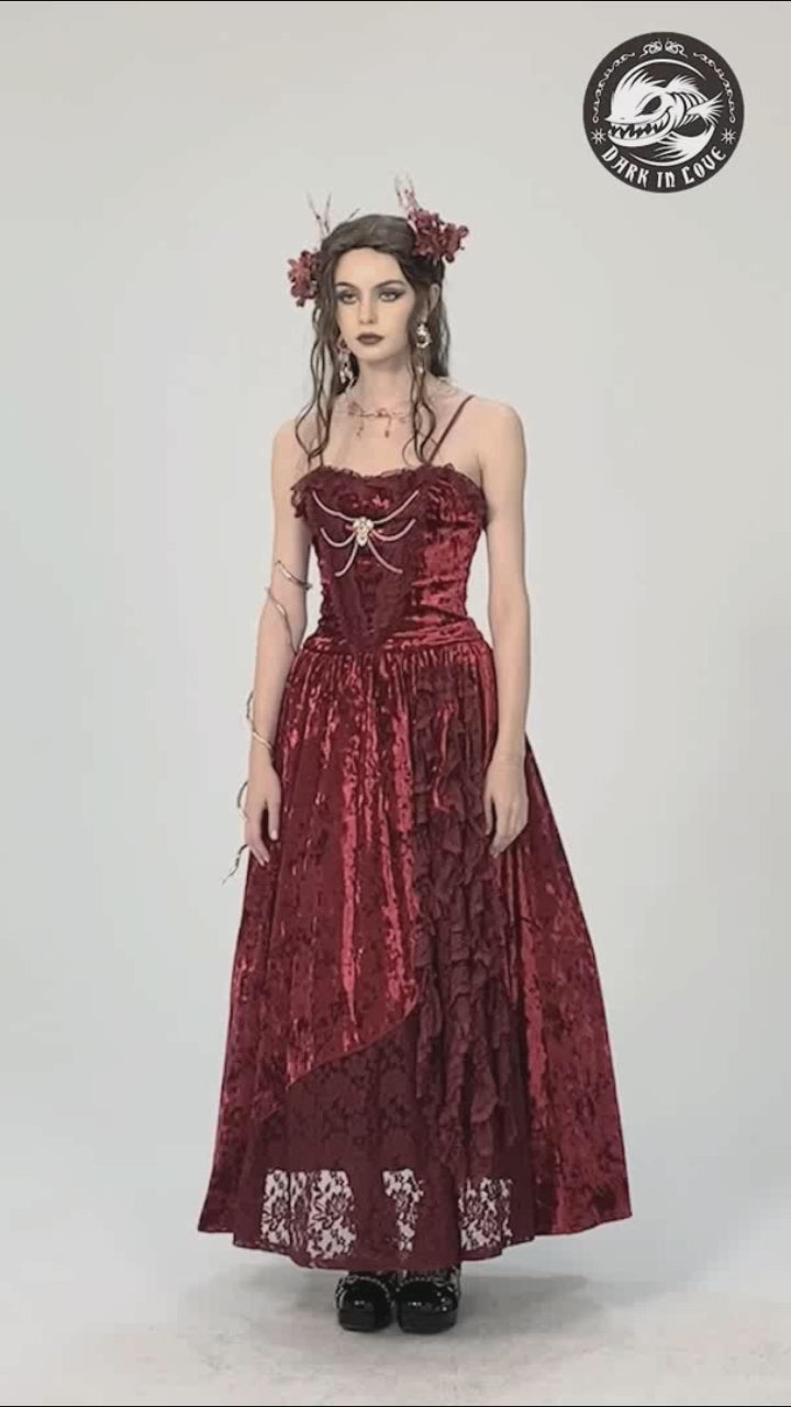 Model wears the Dark in Love DW757 red velvet ballgown, gently moving to show the layered asymmetric hem, corset-style bodice, and soft drape of the crushed velvet fabric.