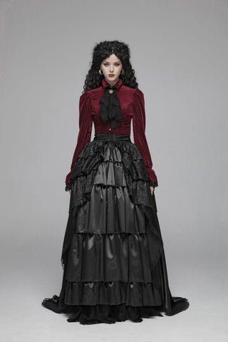 Model in a red striped button-front blouse with puff shoulders, fluted lace cuffs, and a pointed hem, turning to show the corset-laced back on a gray background.