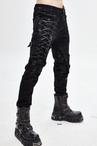 Model wearing slim-fit black distressed pants with lacing down one thigh and buckled straps.