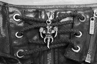Close-up of black cyber-goth hood harness with lace-up neckline, metal zipper and horned skull pendant detail