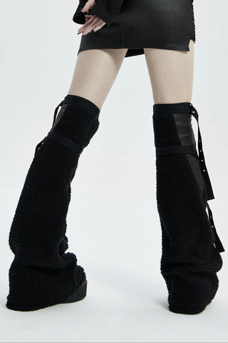Back view of black flared sherpa legwarmers with buckle straps worn over platform boots.