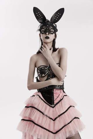 Woman wearing a black faux leather bunny mask with lace eye detail, styled with a black and pink layered Gothic skirt, against a white background.